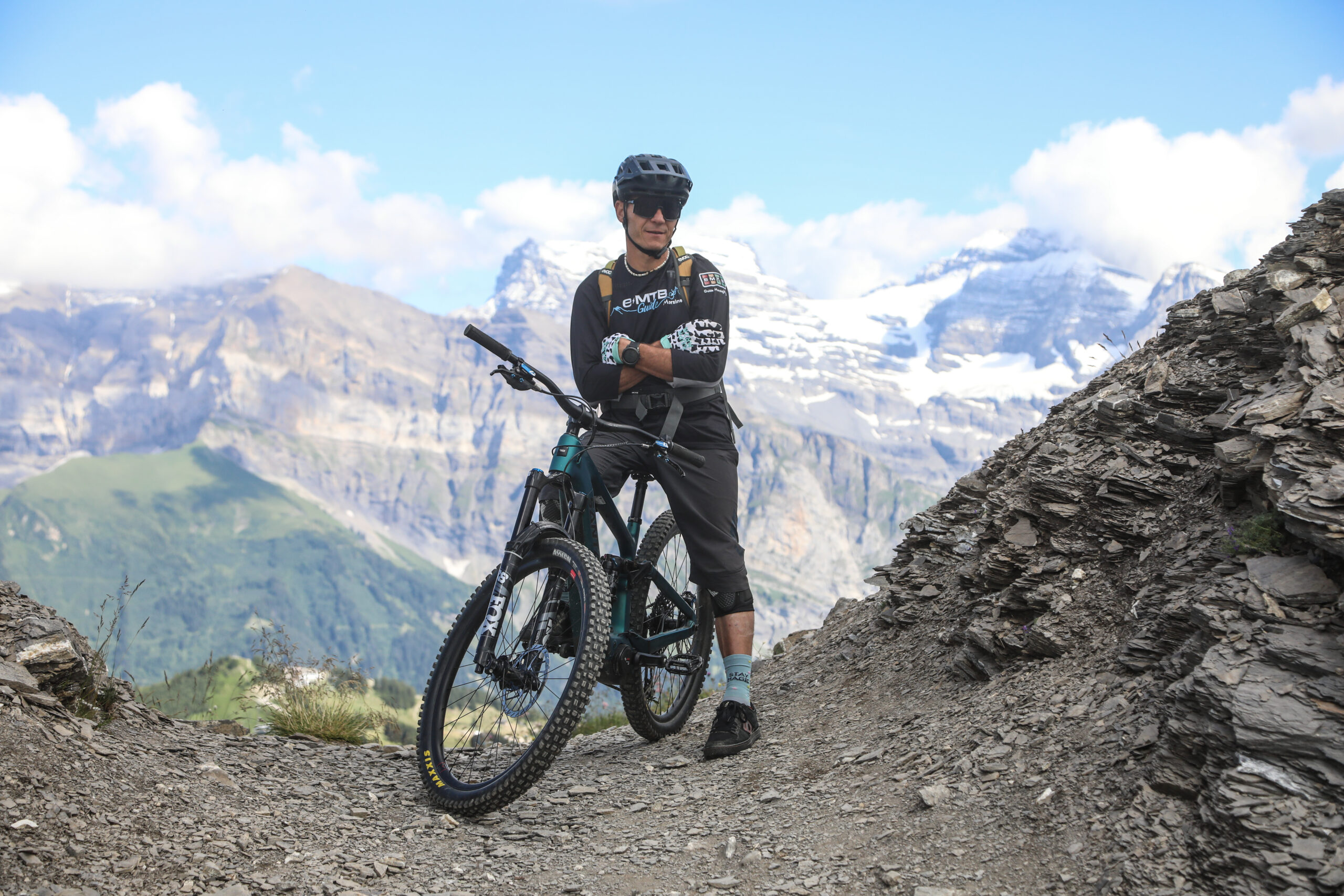 Rider and electric mountain bike below snow-capped peaks, Portes du Soleil Rider and electric mountain bike below snow-capped peaks, Portes du Soleil